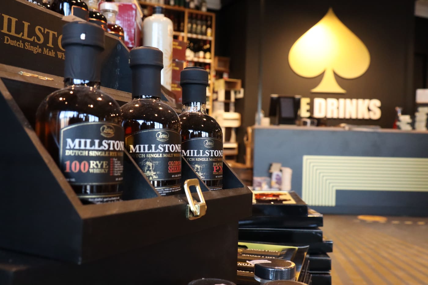 Whisky's van Millstone in de winkel van AceDrinks in Vlissingen, met de toonbank en het schoppenlogo op de achtergrond